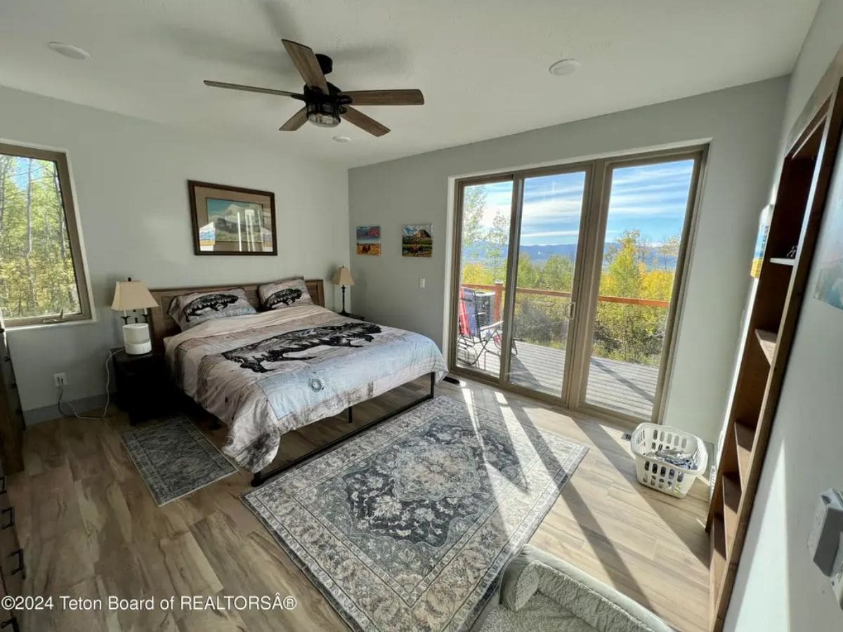 Large bed with neutral bedding is set against a white wall.