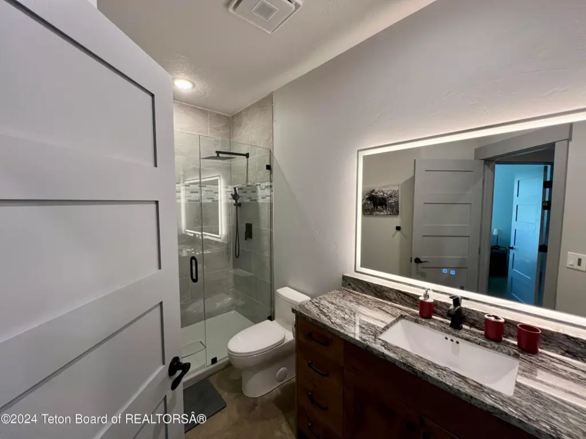 Glass-enclosed shower is positioned next to a toilet.