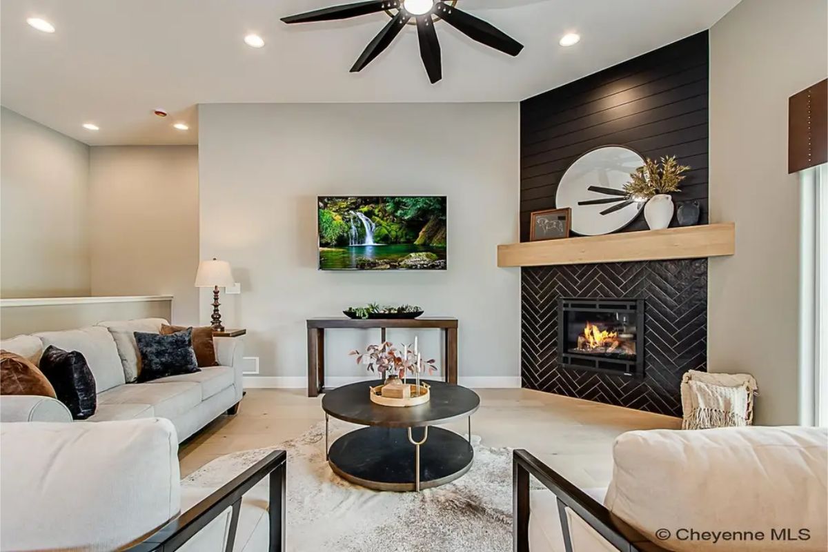 Gas fireplace with a black herringbone tile surround is topped with a light wood mantel.