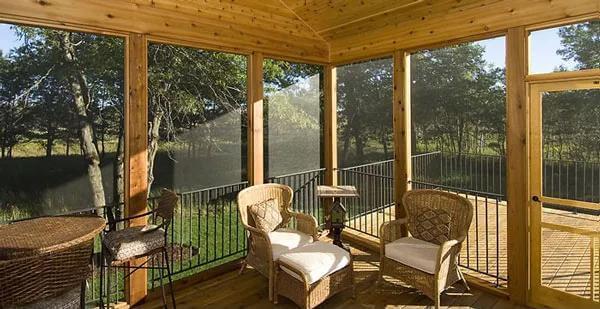 Enjoy a Woodsy Retreat on a Screened-In Porch with Wicker Seating