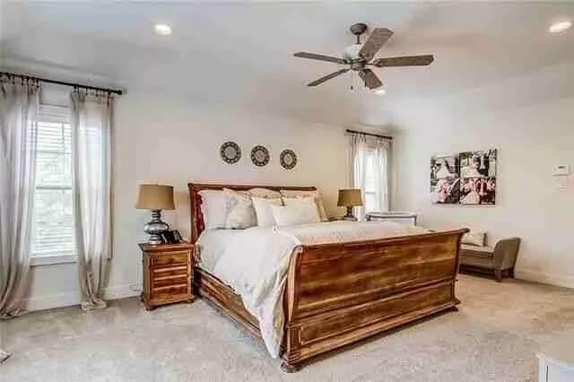 Elegant Bedroom with a Statement Ceiling Fan and Rich Wooden Bed