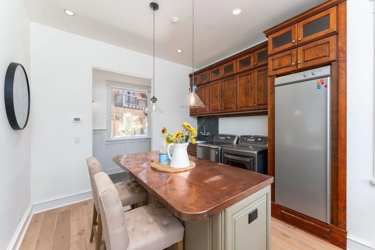 Notice the Copper-Topped Island and Rich Wooden Cabinets in This Multifunctional Space