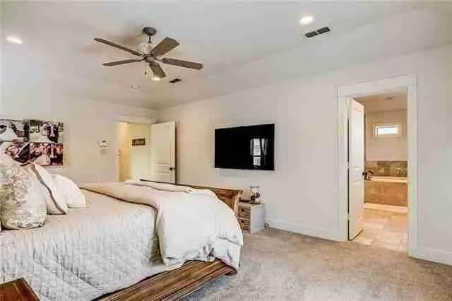 Spacious Bedroom Featuring a Cozy Carpet and Sleek Ceiling Fan