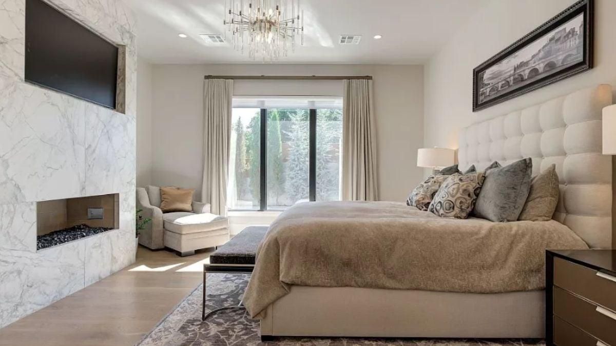 Unwind in This Luxurious Bedroom With a Marble-Accented Fireplace
