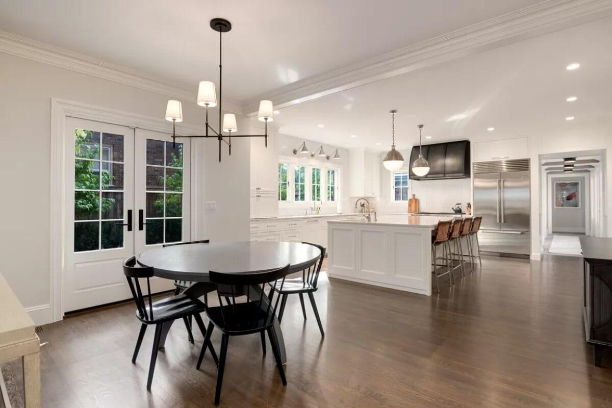 Sleek Kitchen Opens to a Cozy Breakfast Nook With A Black Range Hood Stealing the Show