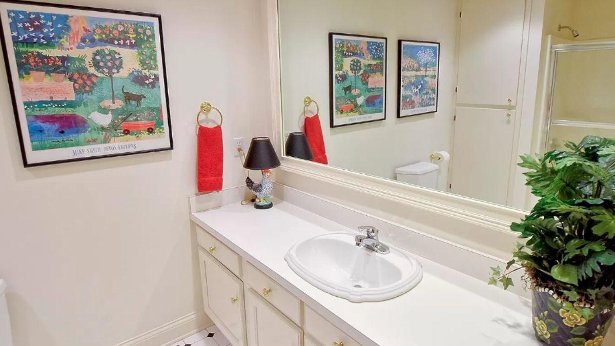 Look at the Whimsical Art and Bold Red Accents in This Bathroom