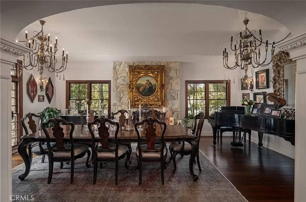 Opulent Dining Area with Grand Chandeliers and a Striking Stone Fireplace