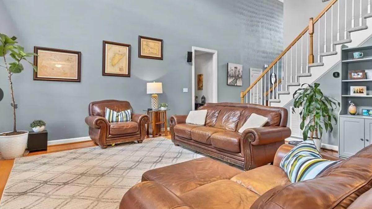 Check Out This Living Room with Leather Furniture and an Inviting Staircase