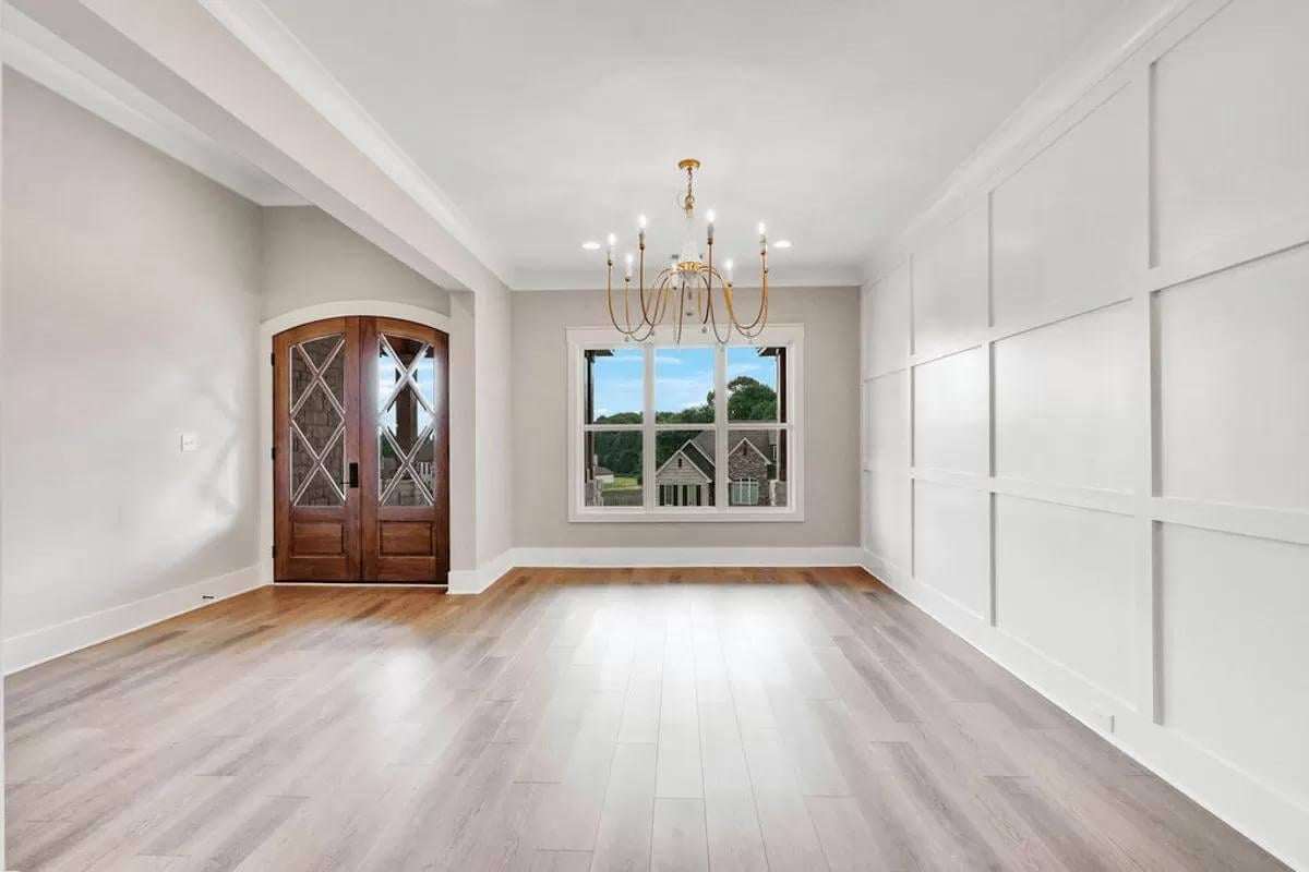 Take Note of the Wooden Doors and Elegant Chandelier in This Stylish Entryway