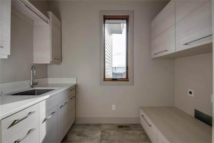 Simple Laundry Room With Sleek Cabinetry and a Linear Window