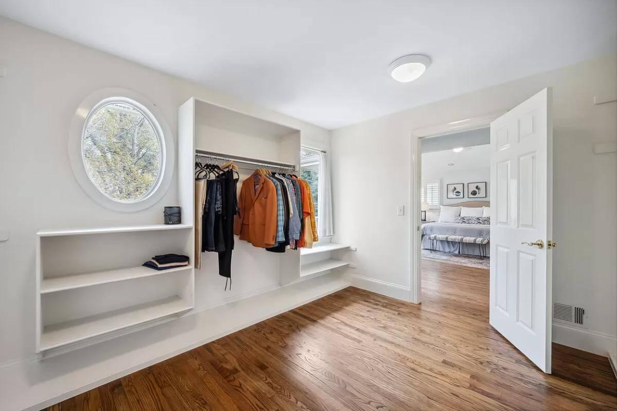 Spot the Unique Oval Window in This Bright Walk-In Closet