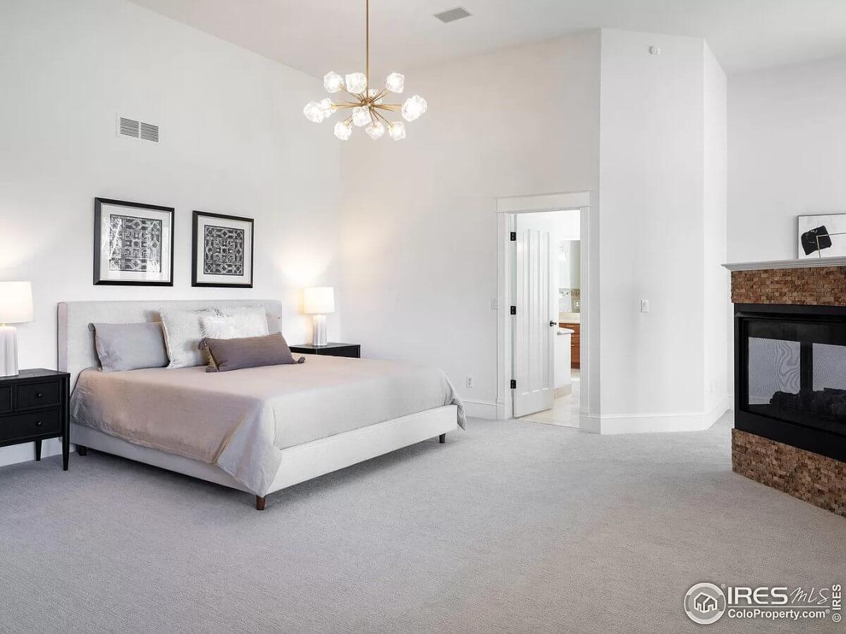 Spacious Bedroom with a Modern Fireplace and Eye-Catching Chandelier