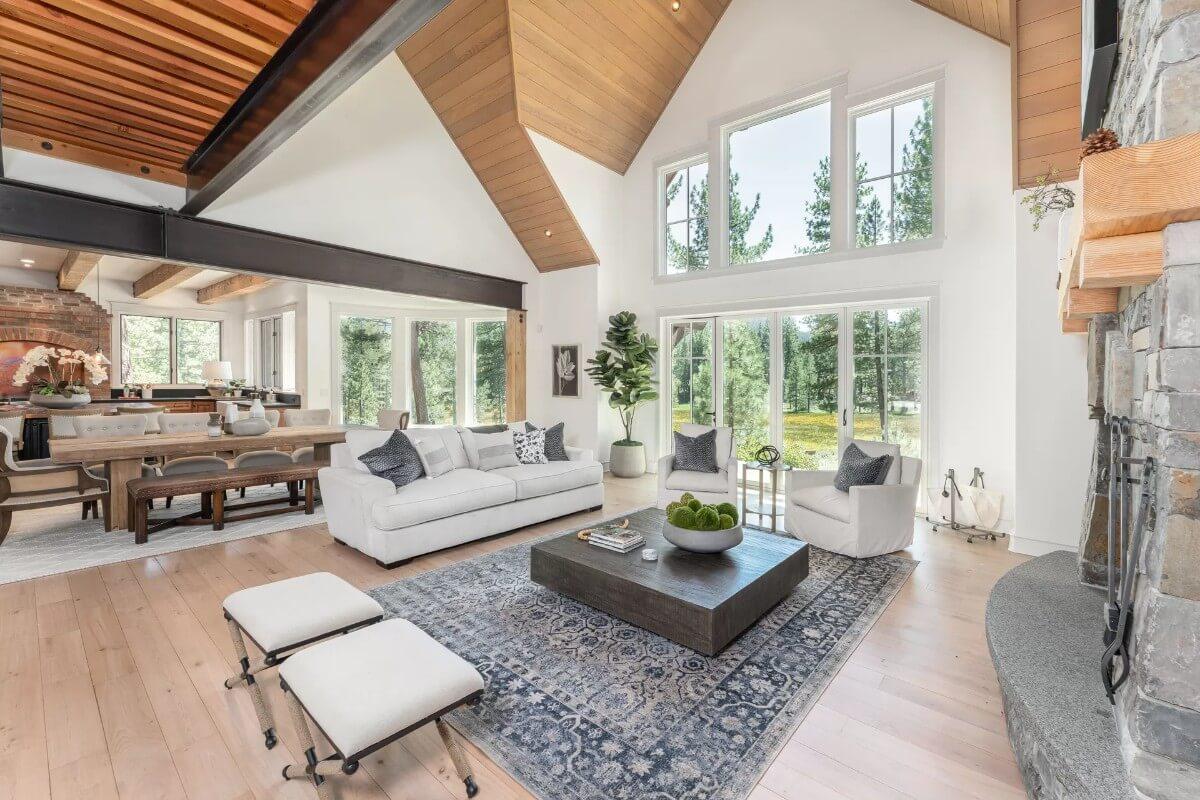 Grand Living Room with Vaulted Ceilings and Expansive Windows Offering Forest Views