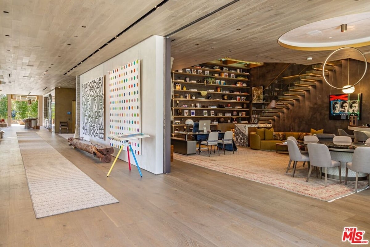 Hallway and reading nook with large bookshelves, dining table, and modern lighting. 