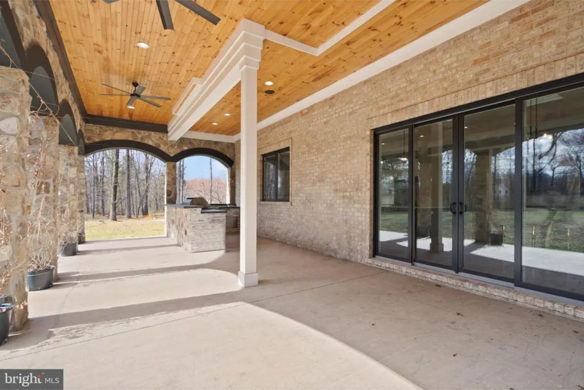 Covered patio with brick walls, wood ceiling, ceiling fans, and access to backyard. 