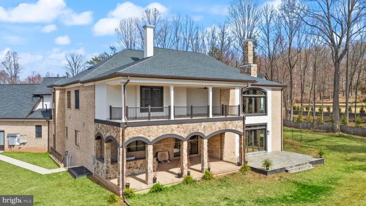 Rear exterior view of two-story home with arched patio columns and upper-level balcony. 