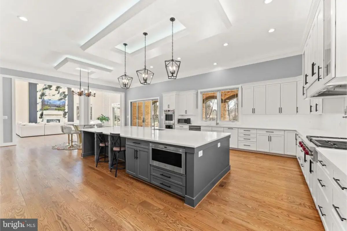 Kitchen with large central island, white cabinetry, and pendant lighting. 
