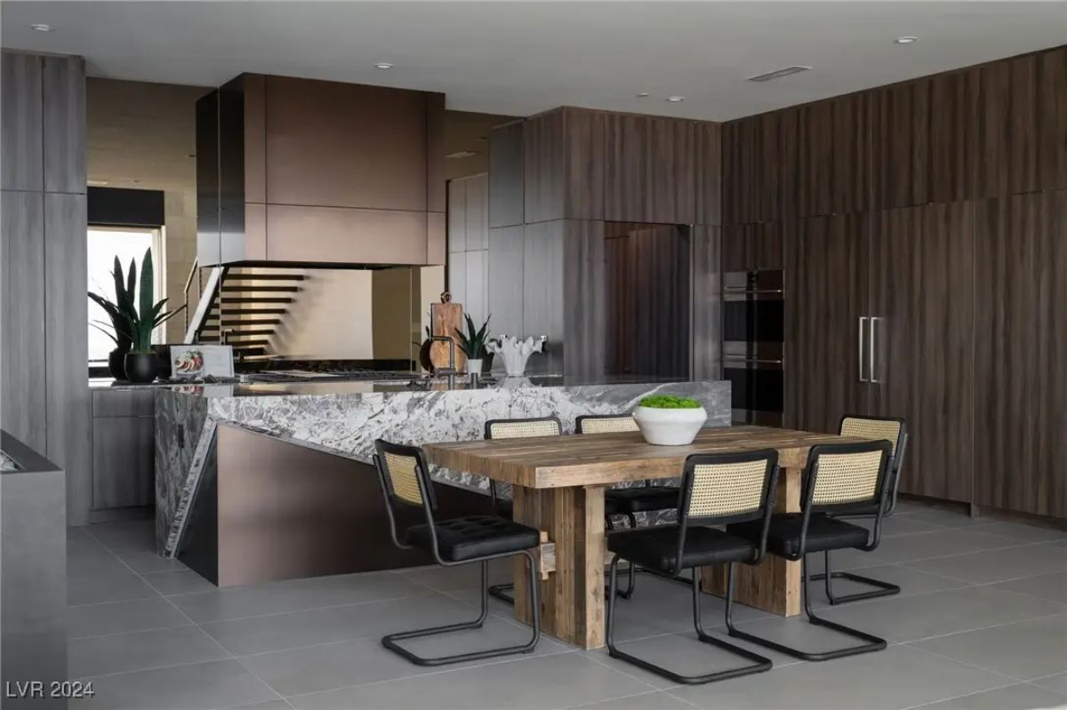 Kitchen with waterfall marble island, wood cabinetry, and concealed appliances.