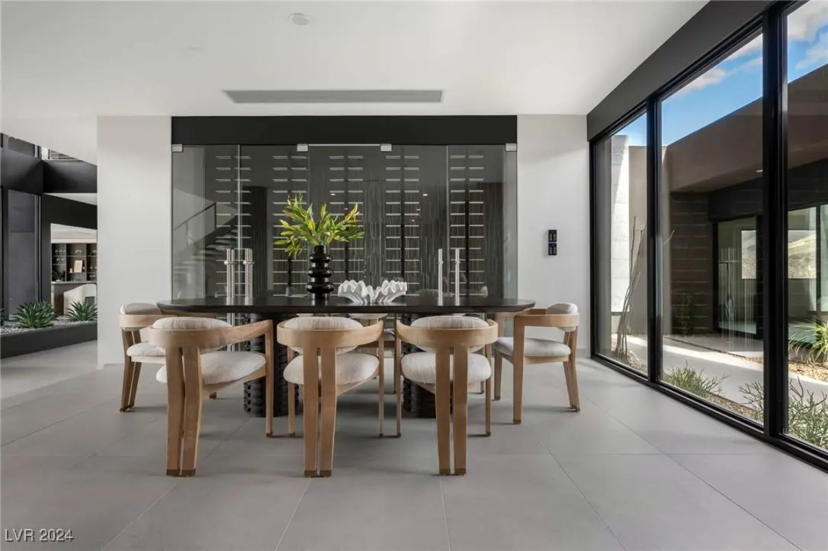 Dining area with glass-enclosed wine storage wall and floor-to-ceiling windows.