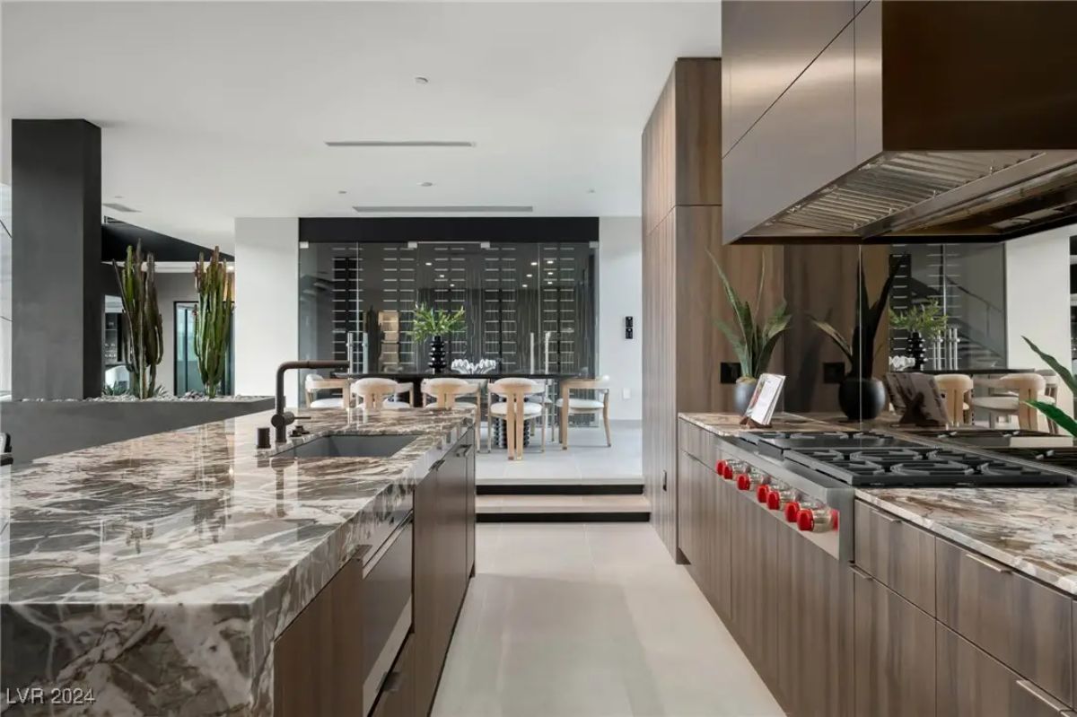 Cooktop view featuring marble counters, vent hood, and proximity to dining area.