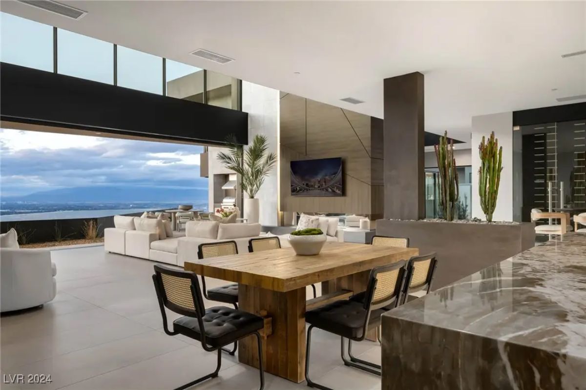 Secondary dining area with wood table, leather chairs, and mountain views beyond open living space.
