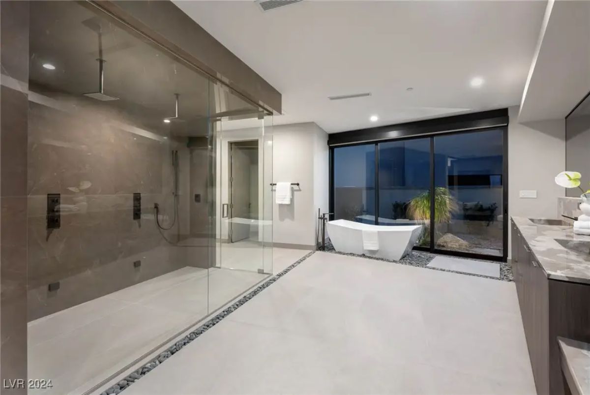Large primary bathroom with expansive glass shower, freestanding tub, and dual vanity.