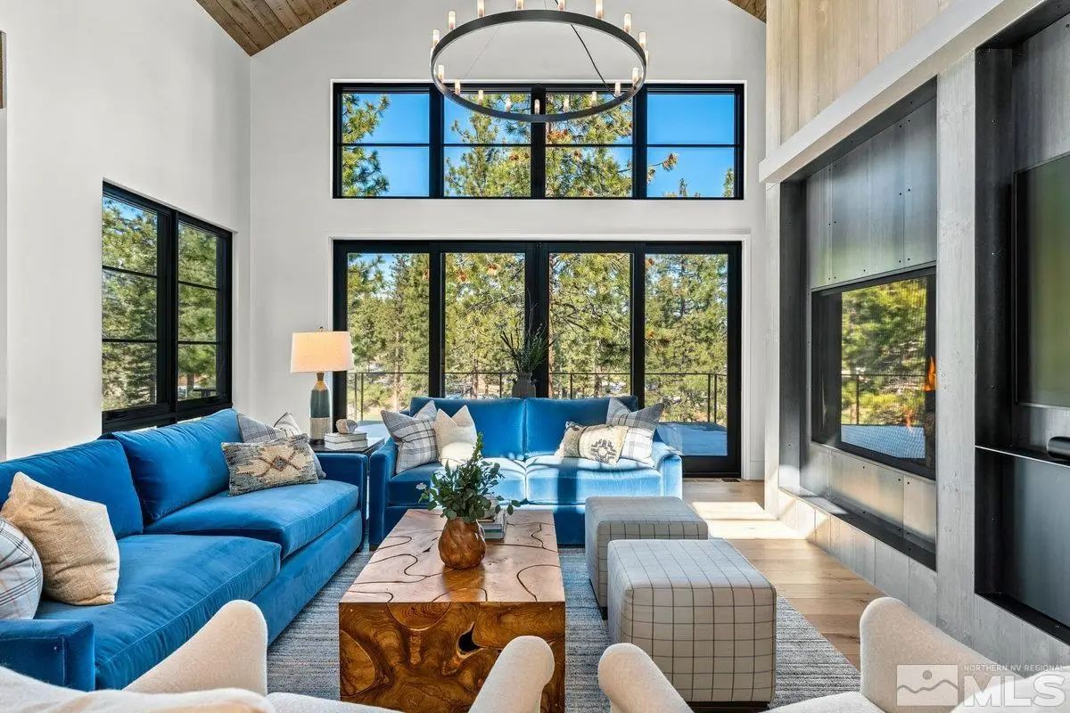 Living room with vaulted ceiling, large windows, and bright blue sectional sofa. 