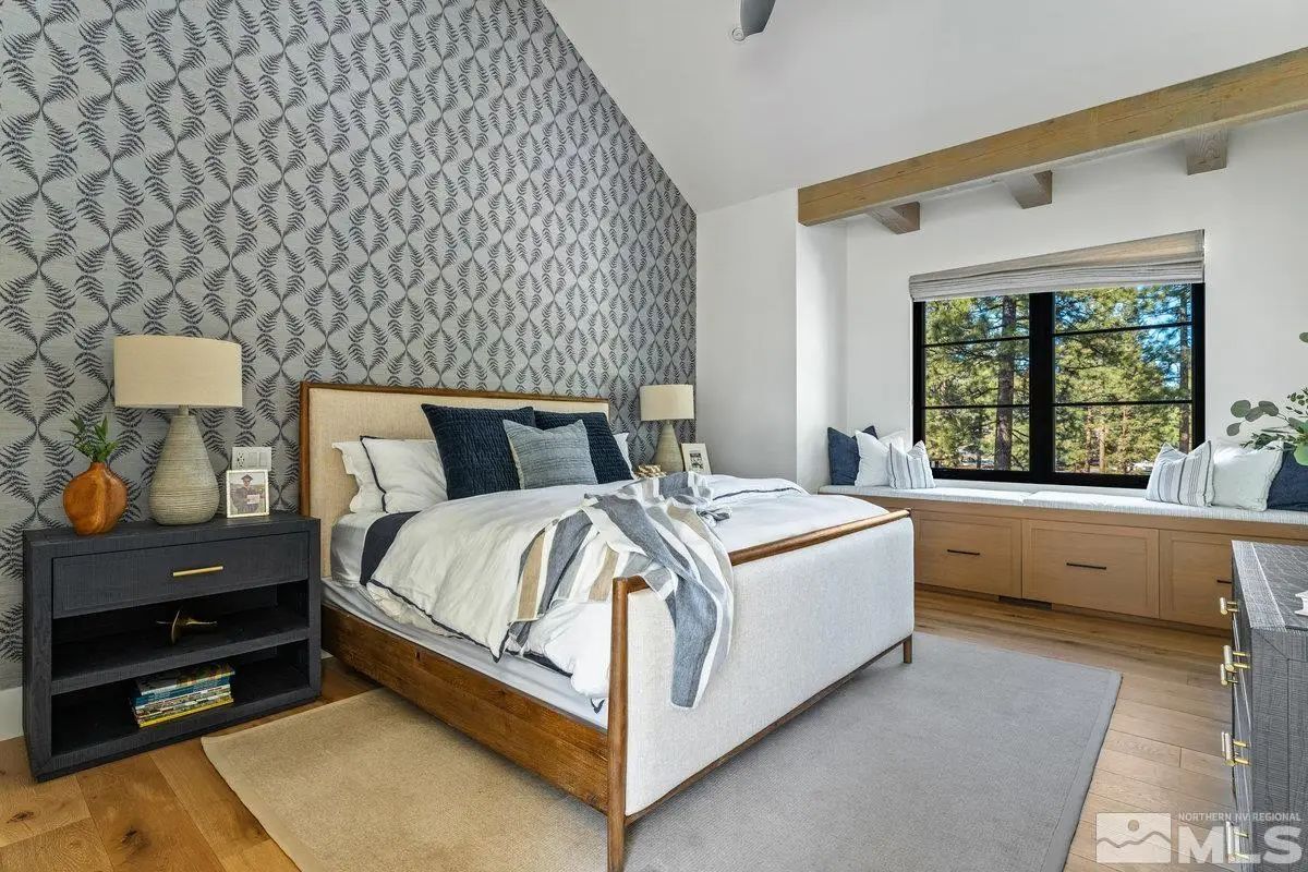 Bedroom with patterned accent wall, vaulted ceiling, and built-in window seat. 