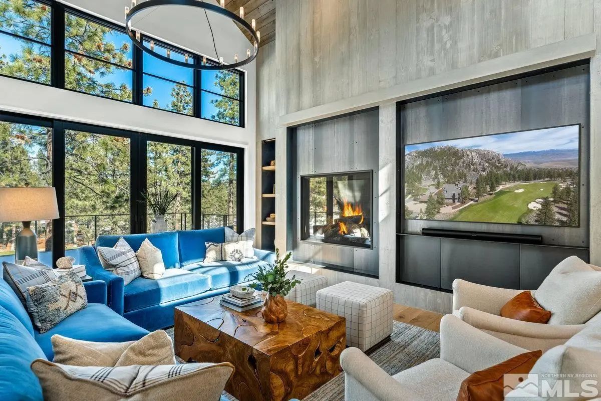 Alternate angle of living room featuring TV wall, modern fireplace, and tree views. 
