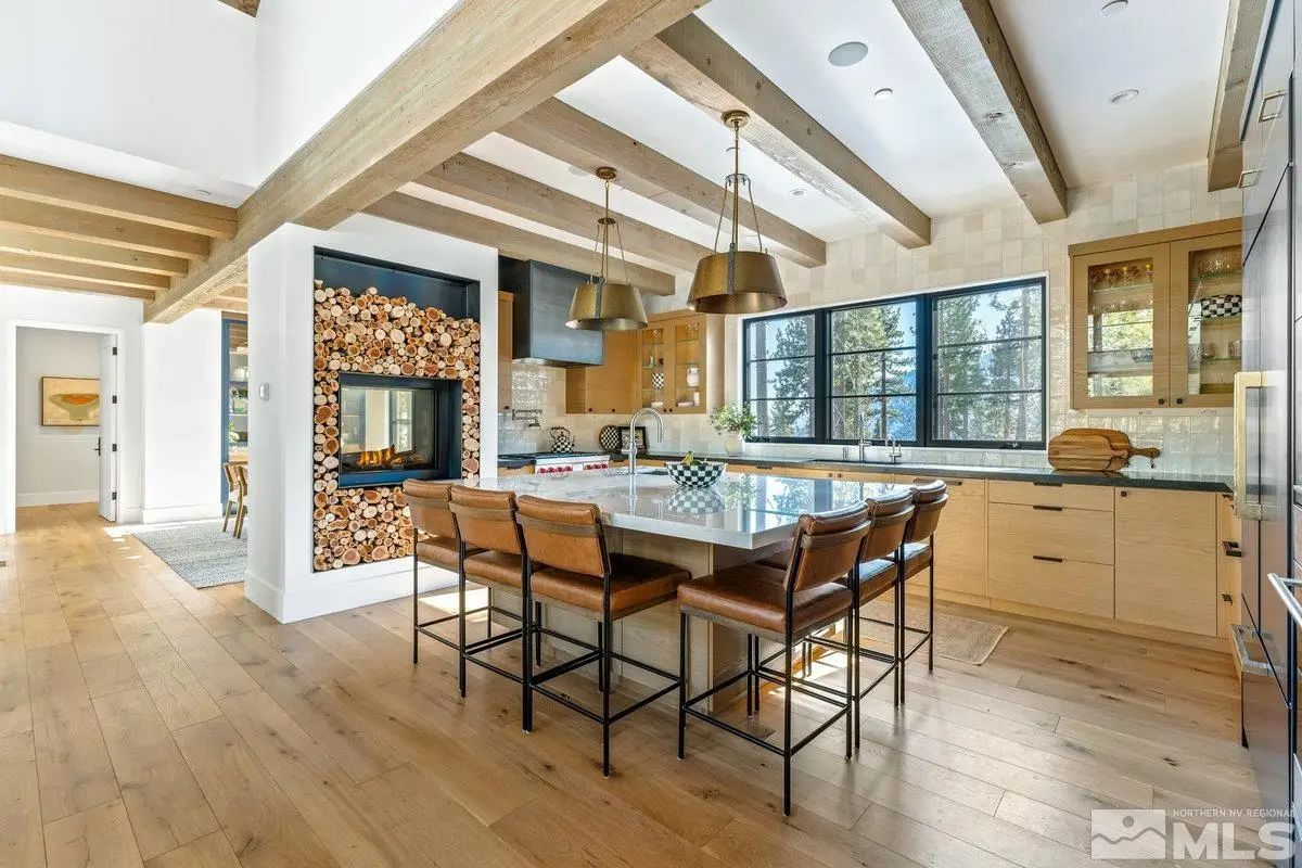 Kitchen with wood cabinetry, island seating, and double-sided fireplace feature. 