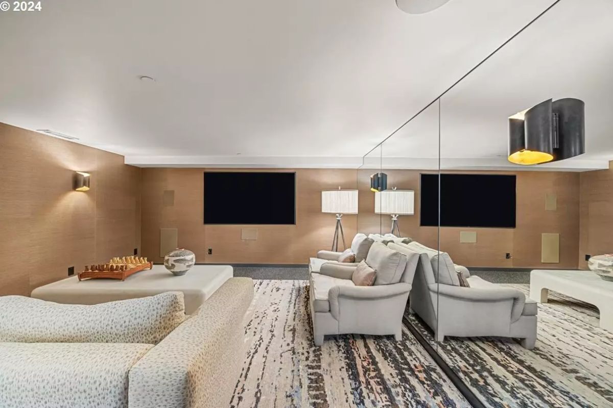 Theater lounge with layered seating, patterned carpet, and mirrored wall. 