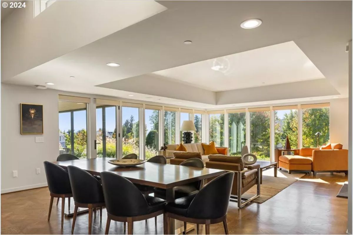 Family dining and living space surrounded by glass walls. 