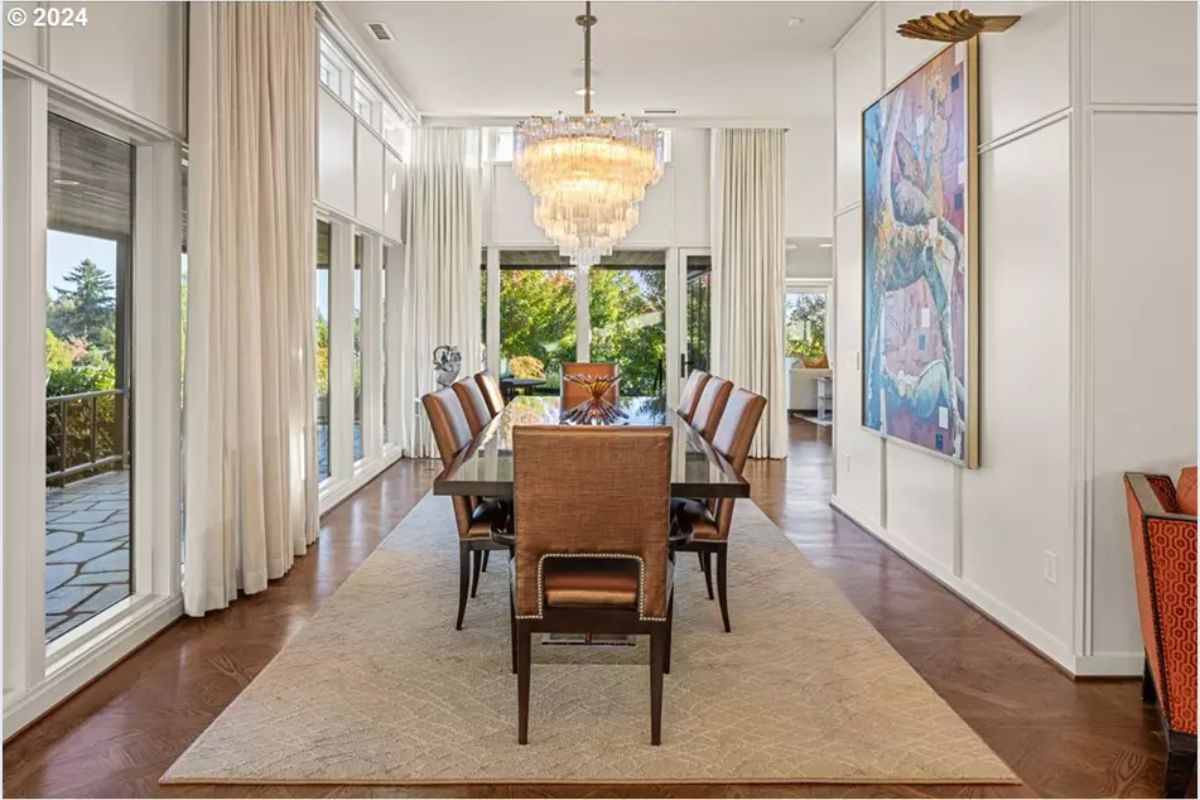 Formal dining space with crystal chandelier and double-height drapes. 