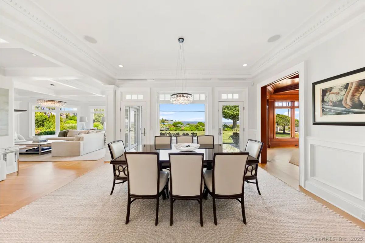 Formal dining room with large windows, coastal views, and access to both living and sunroom spaces. 