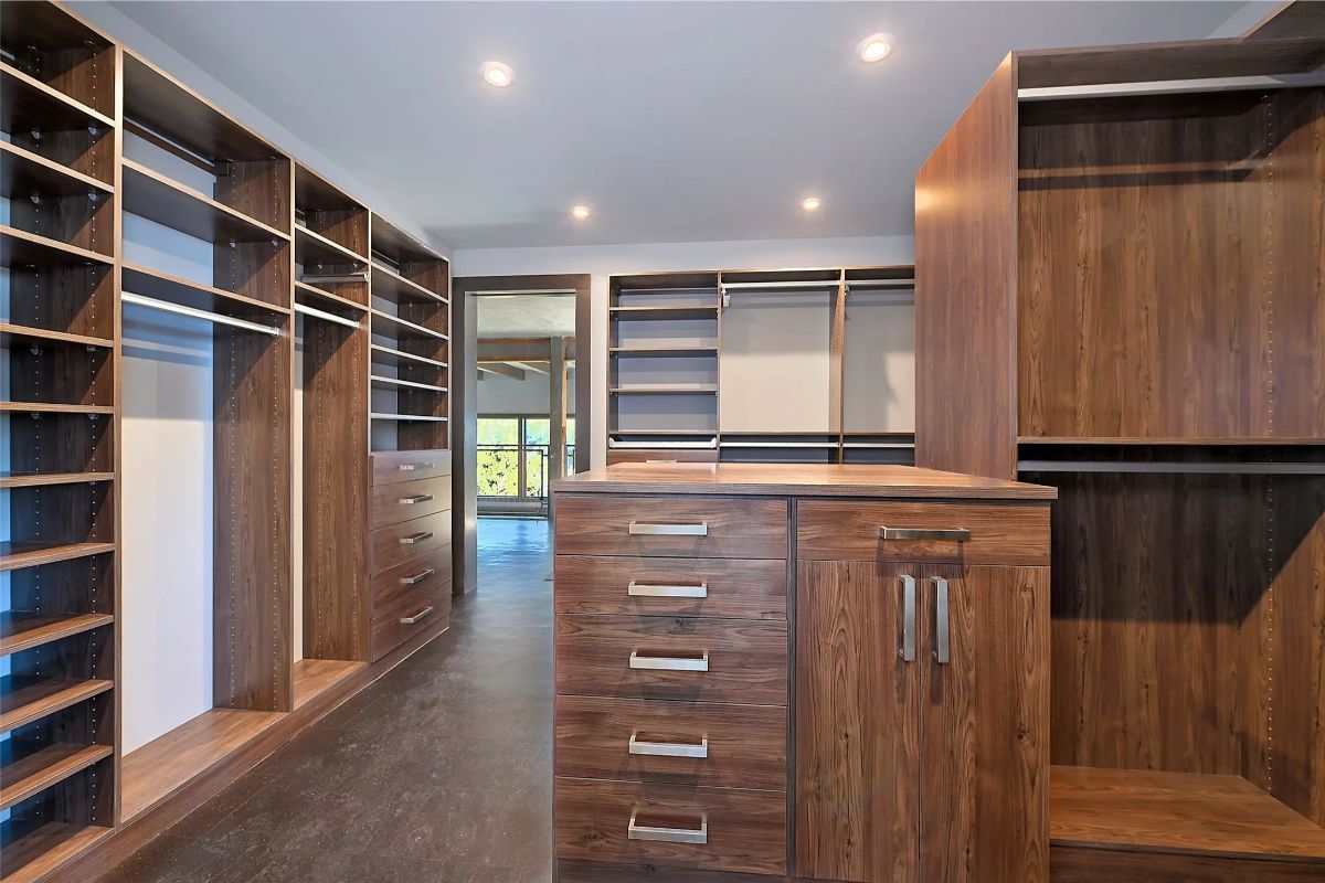  Walk-in closet with rich wood cabinetry, center island, and custom shelving throughout. 