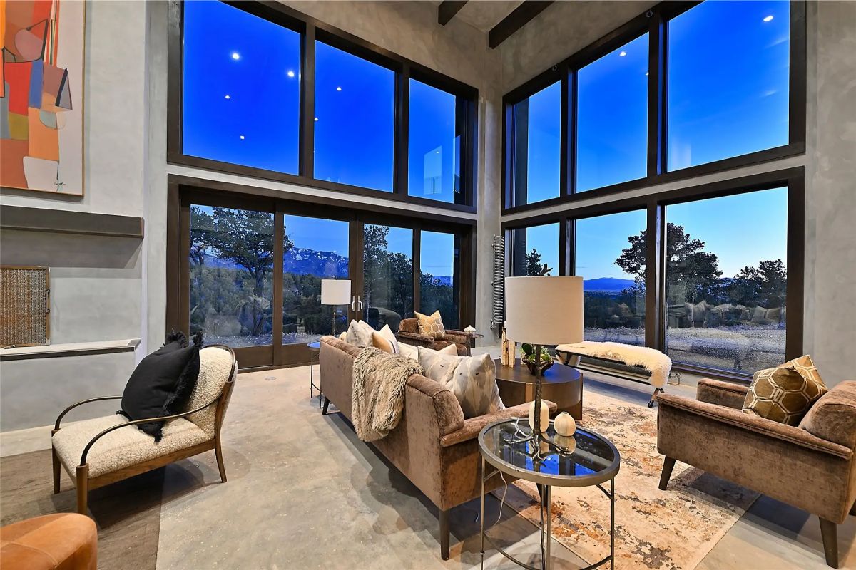 Living room with floor-to-ceiling windows, modern furniture, and sunset mountain views. 