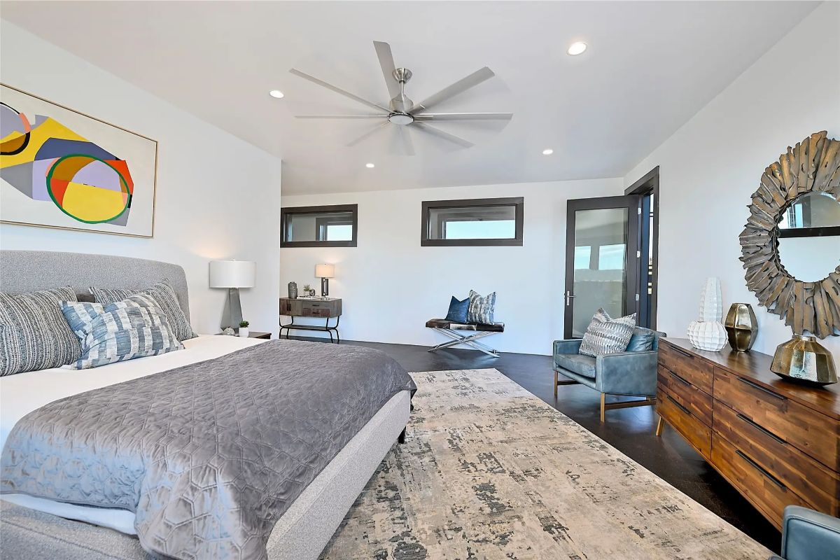 Primary bedroom with ceiling fan, wall art, and sliding door to outdoor space. 