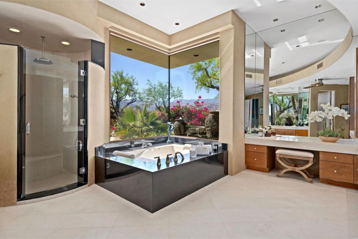 Luxurious bathroom with a corner jetted tub, walk-in shower, and panoramic mountain views. 