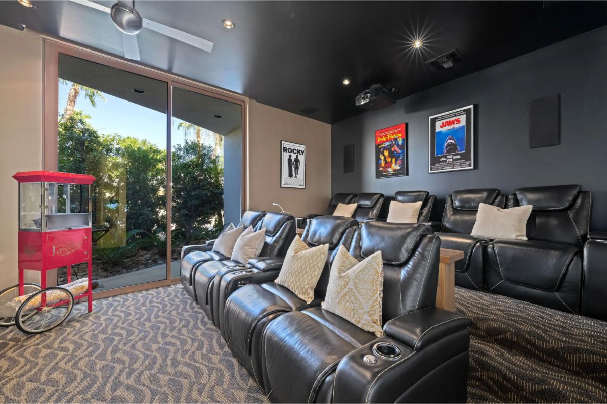 Home theater with leather recliners, wall-mounted posters, and popcorn machine. 