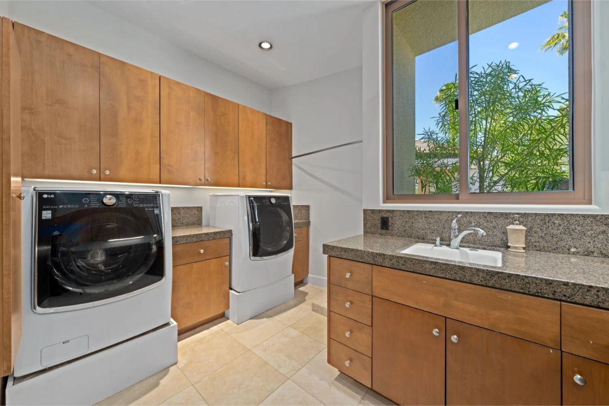 Laundry room with double front-loading machines and upper and lower cabinetry. 