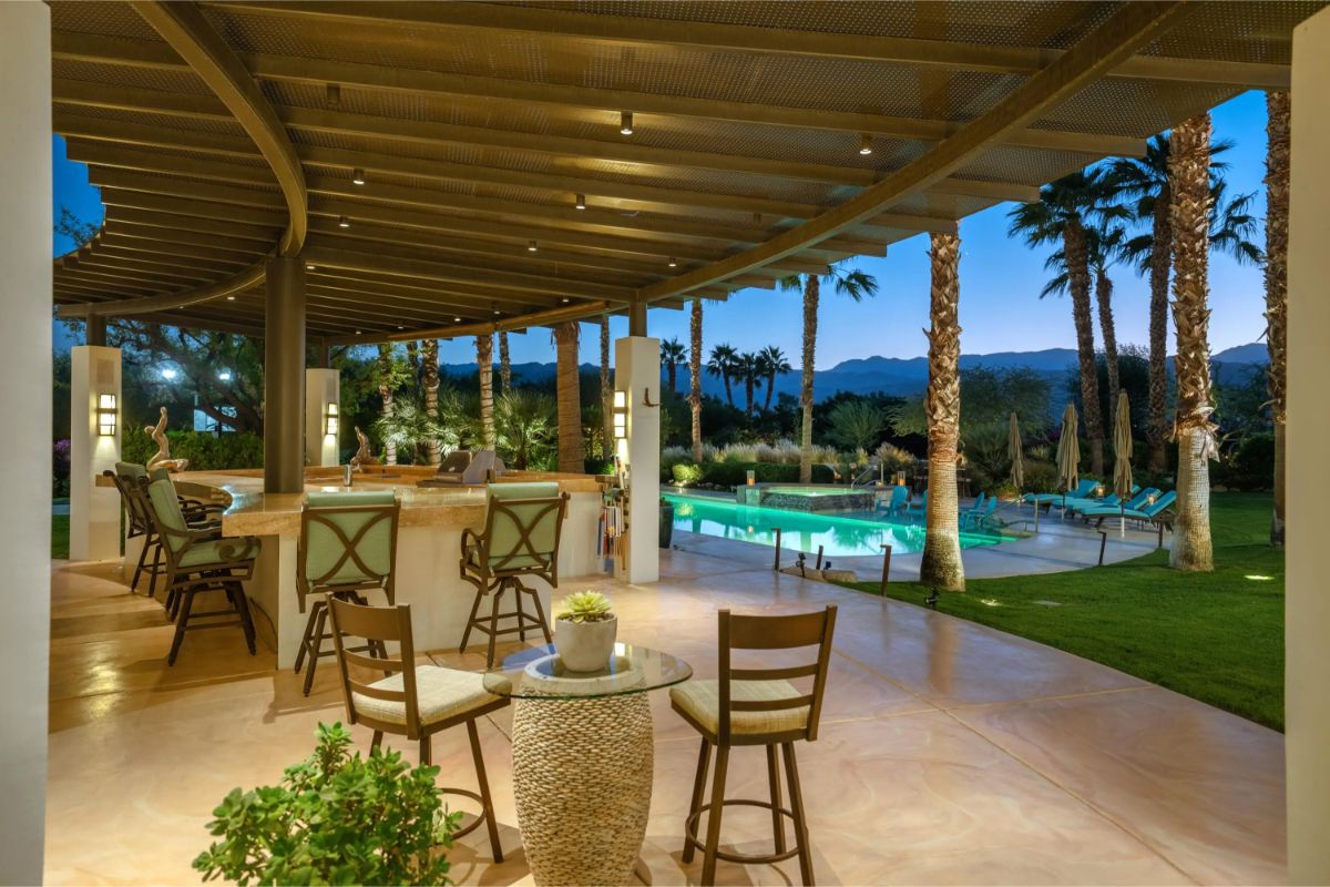 Bar and lounge area under a trellised patio overlooking the pool. 