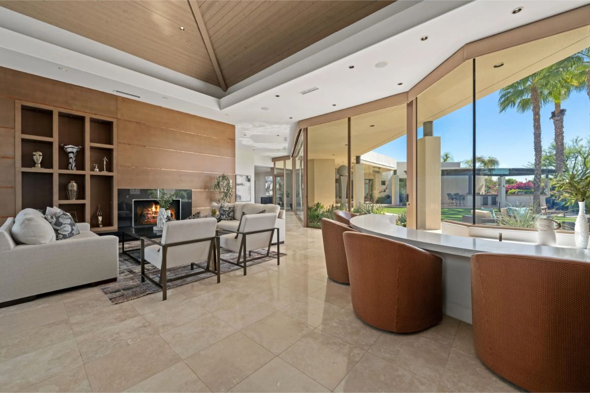 Open living room with large windows, fireplace, and contemporary furnishings offering outdoor views. 