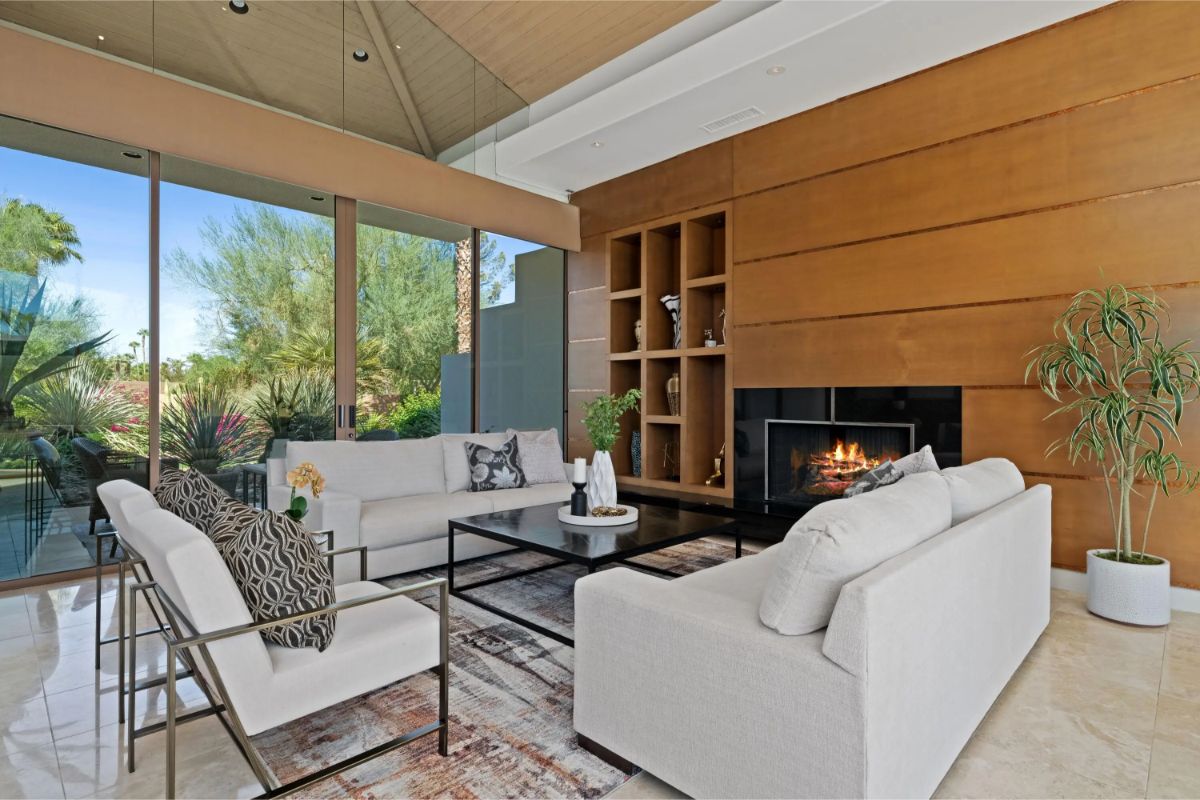 Cozy seating area with built-in shelving and modern fireplace framed by floor-to-ceiling glass. 