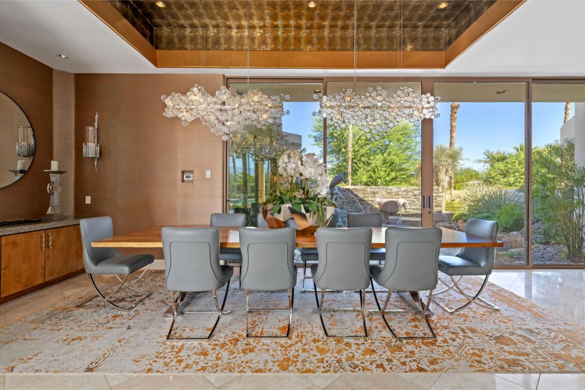 Formal dining room with modern chandelier lighting and sliding glass doors leading to the outdoors. 