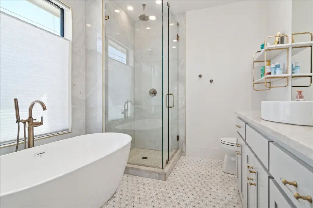 Bathroom with freestanding tub, glass-enclosed shower, and gold fixtures. 