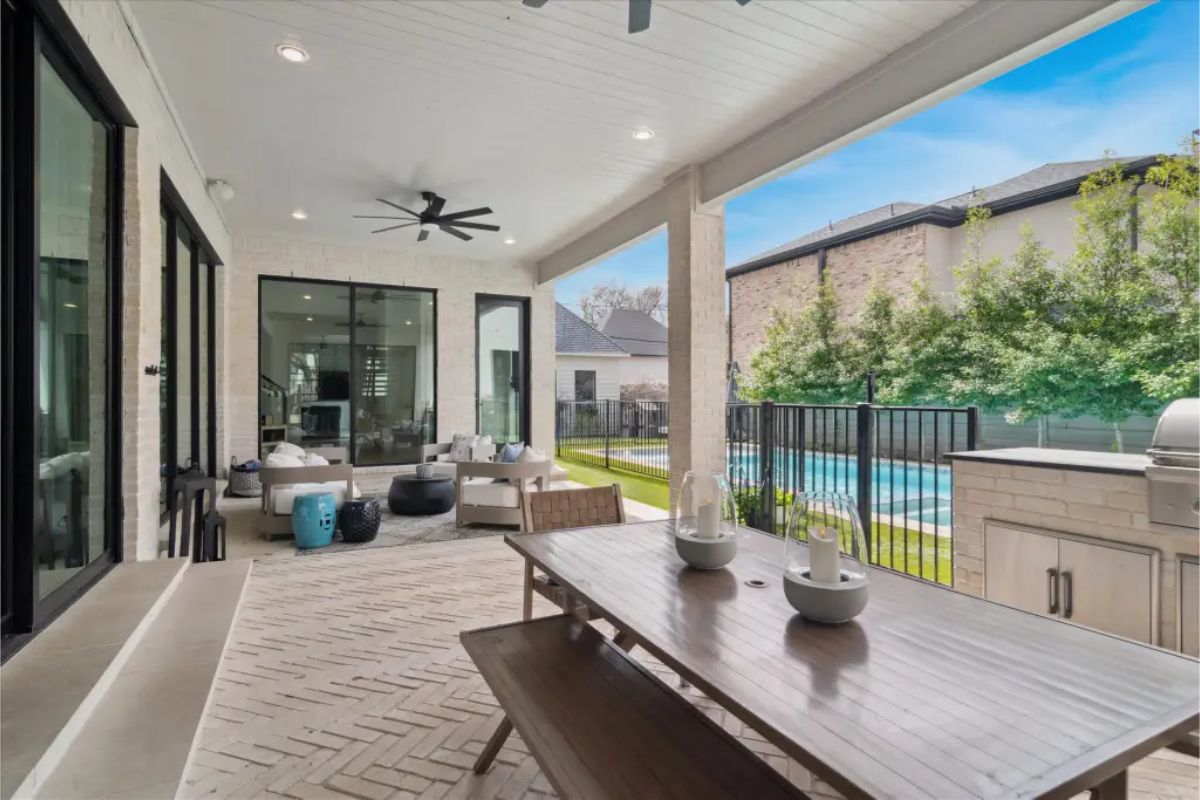 Covered patio with dining table, outdoor seating, ceiling fans, and view of pool. 