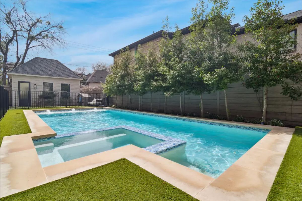 Rectangular swimming pool with integrated spa and surrounding artificial turf. 