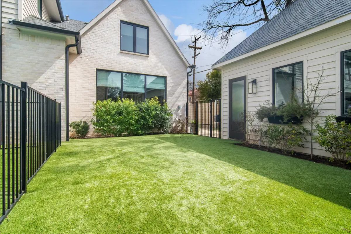 Small artificial turf yard between house and detached building. 