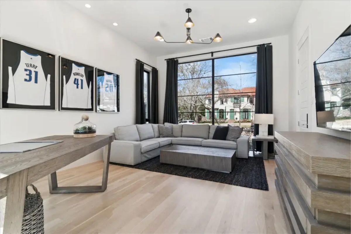 Office or media room with L-shaped sofa and framed jerseys on wall. 