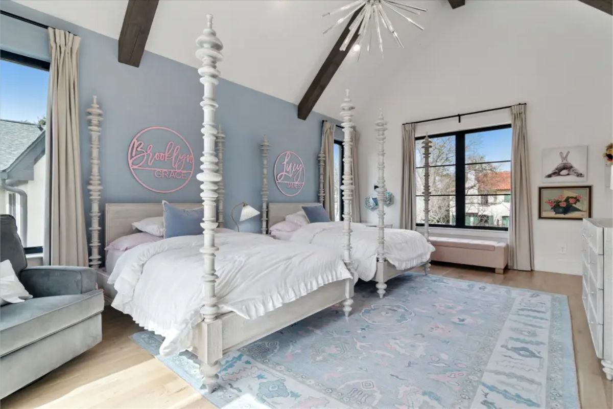 Bedroom with two canopy beds, vaulted ceiling with beams, and wall-mounted name signs. 